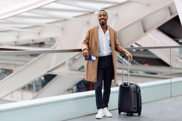 Handsome Smiling Black Man Waiting For Flight In Airport Terminal