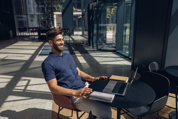 Photo handsome smiling entrepreneur working on laptop sitting in coworking during working day