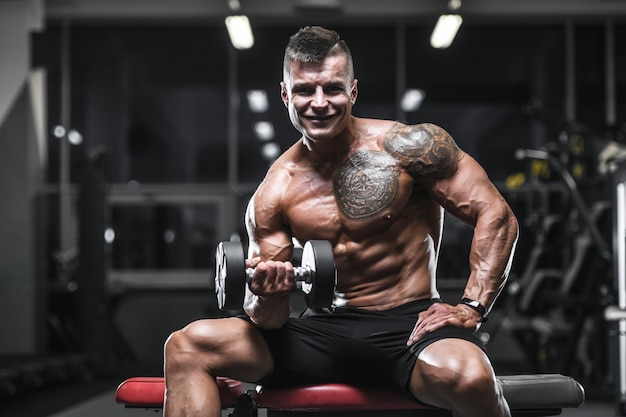 Handsome strong bodybuilder athletic men pumping up muscles with dumbbells