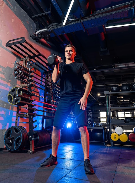 Handsome strong man training hard in the gym Young healthy man doing exercise in gym