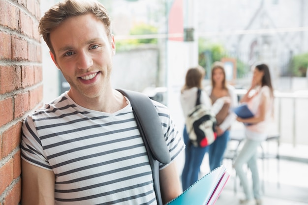 Handsome student smiling and holding notepads