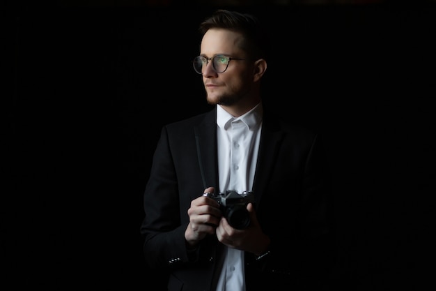 Photo handsome and stylish man in white shirt and black suit holding vintage photo camera