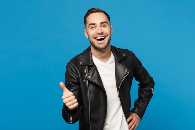 Handsome stylish young bearded man in black leather jacket white t-shirt looking camera isolated on blue wall background studio portrait. People sincere emotions lifestyle concept. Mock up copy space.