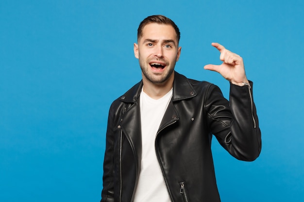 Handsome stylish young unshaven man in black leather jacket white t-shirt looking camera isolated on blue wall background studio portrait. People sincere emotions lifestyle concept. Mock up copy space