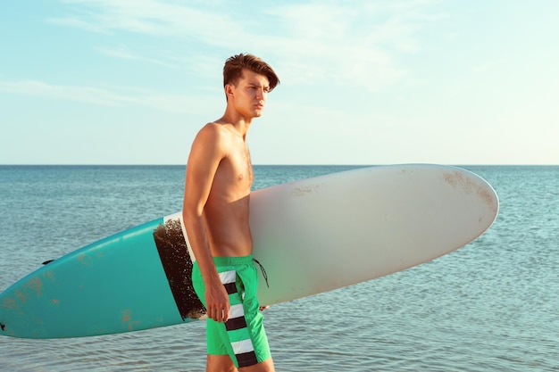 Handsome surfer holding his surfboard