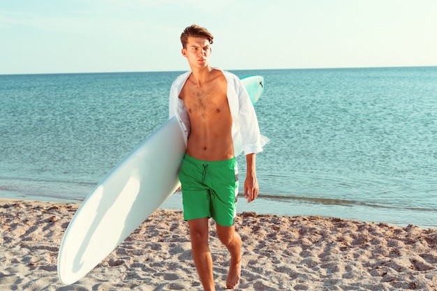 Handsome surfer holding his surfboard