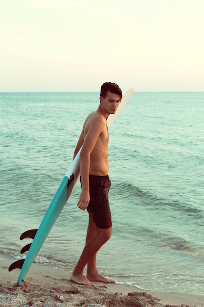 Handsome surfer holding his surfboard