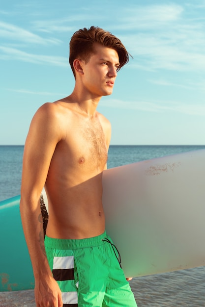 Handsome surfer holding his surfboard