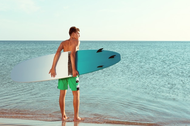 Handsome surfer holding his surfboard