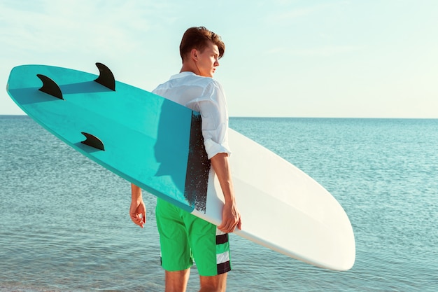 Handsome surfer holding his surfboard