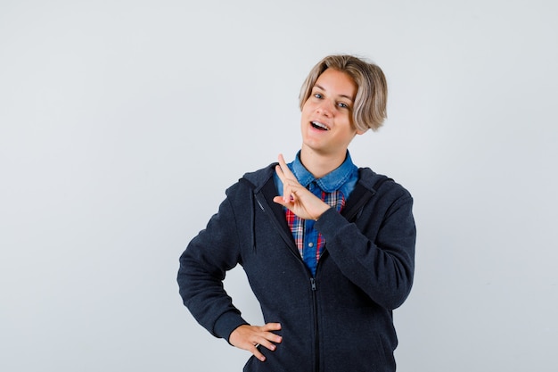 Handsome teen boy showing V-sign in shirt, hoodie , front view.