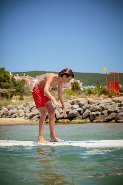 Handsome teenage boy having fun floating on a swim board