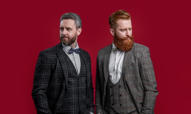 handsome tux men with bowtie isolated on burgundy background two men in tux bowtie studio shot of men wearing bowtie and tux elegant men in formal tux suit with bowtie