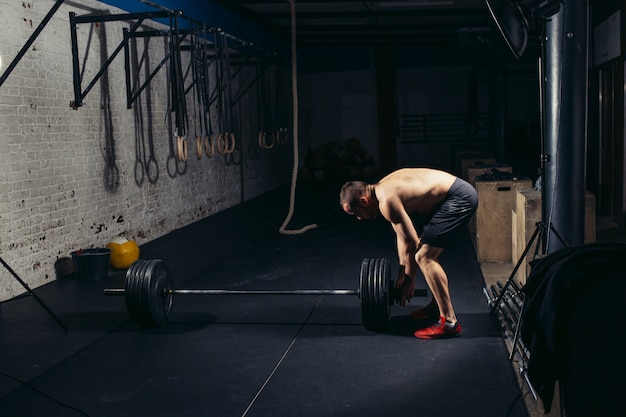 Handsome weightlifter preparing for training with barbell