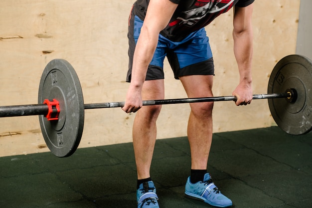 Handsome weightlifter preparing for training with barbell