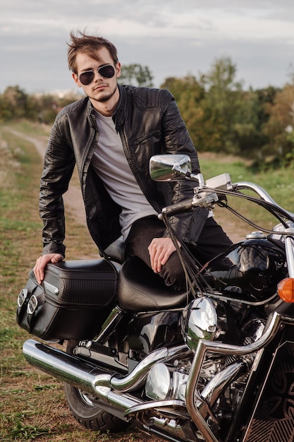 Handsome yong male is sitting on his motor bike outdoors