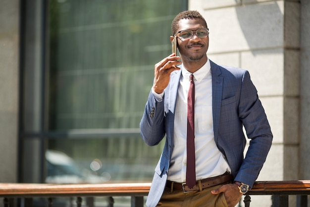 handsome young adult african man in suit and glasses talking on the phone