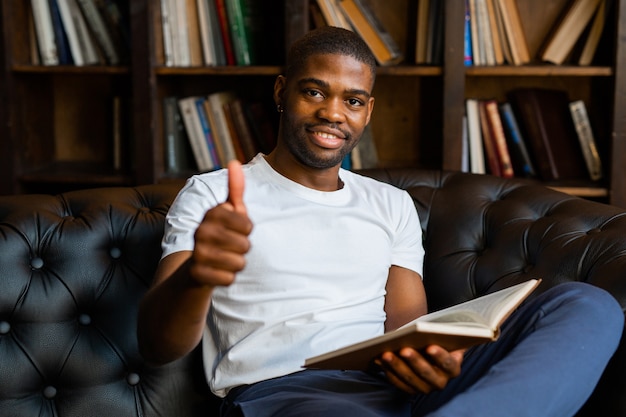 handsome young african man reading book with hand gesture