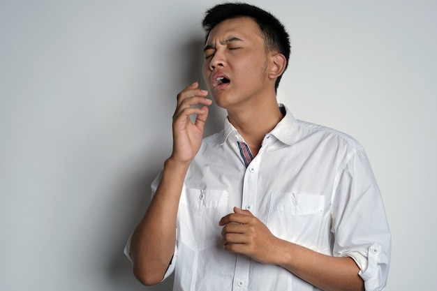 handsome young asian man is going to sneezing with his hand trying to covering his mouth