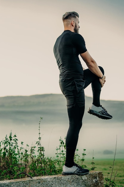 Handsome young beard man stretching in nature