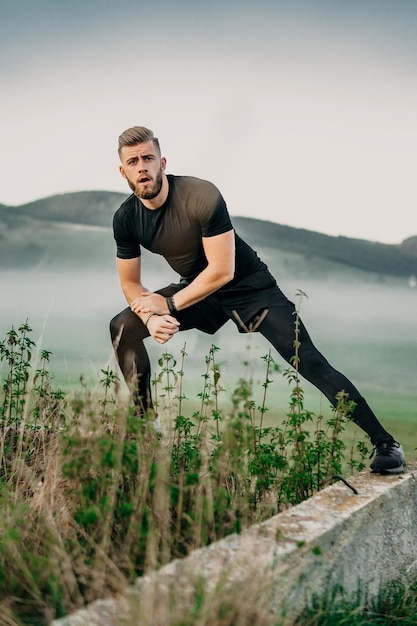 Handsome young beard man stretching in nature