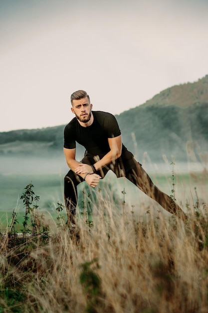 Handsome young beard man stretching in nature