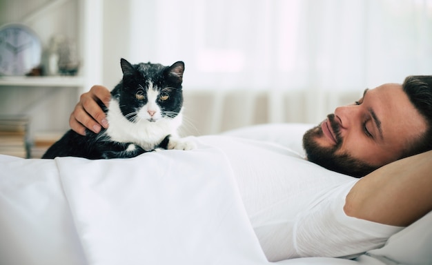 Handsome young bearded man is sleeping in a white big bed in a comfortable bedroom