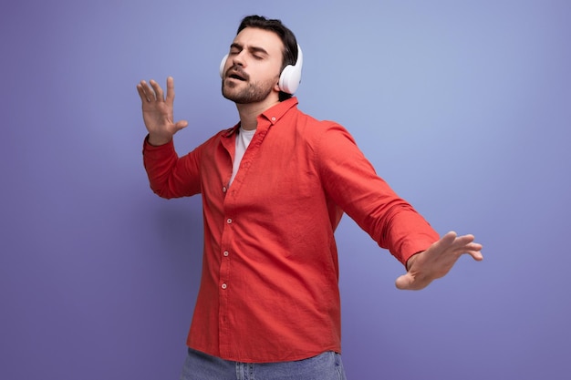 Handsome young brunette man listening to music in wireless headphones on the background with copy