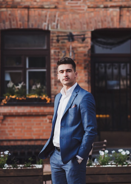 Handsome young brunette model, wearing suit, looking at camera, posing in city. Businessman portrait.