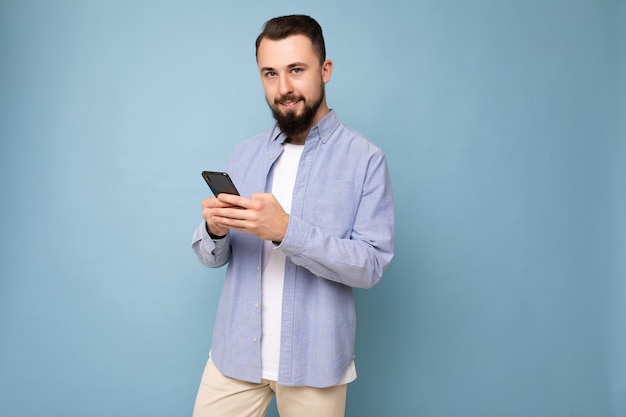 Handsome young brunette unshaven man with beard wearing stylish white tshirt and blue shirt isolated