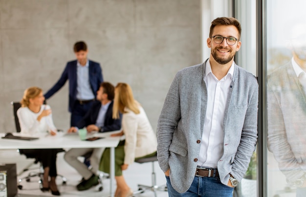 Photo handsome young business man standing confident in the office in front of his team