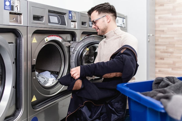 Handsome young businessman doing his weekly washing in a laundromat.