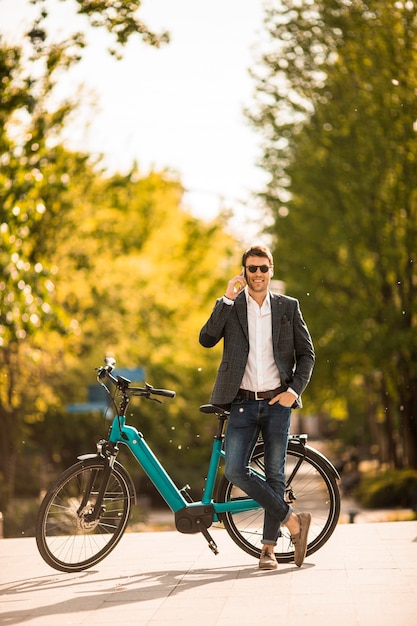 Handsome young businessman on the ebike using mobile phone