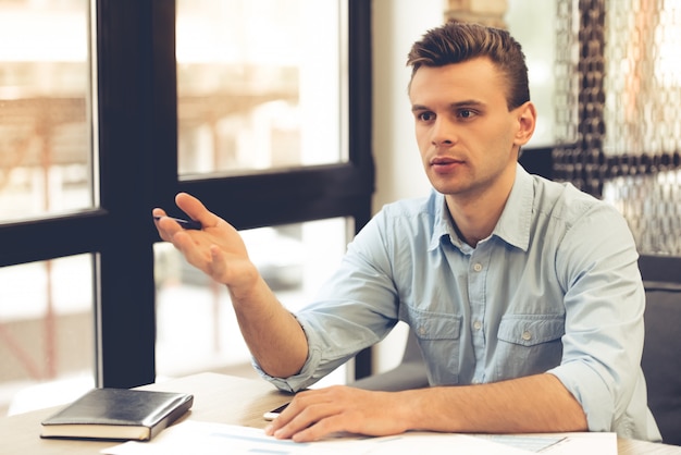 Handsome young businessman is pointing away