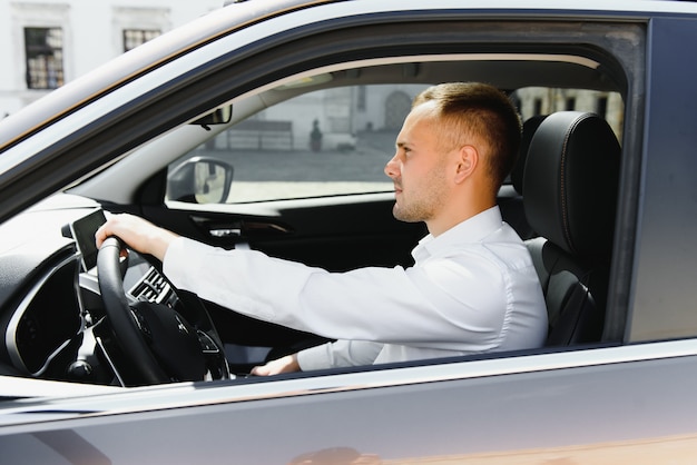 Handsome young businessman sitting in his new car