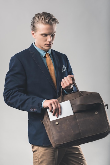 Handsome young businessman with stylish leather briefcase and tablet