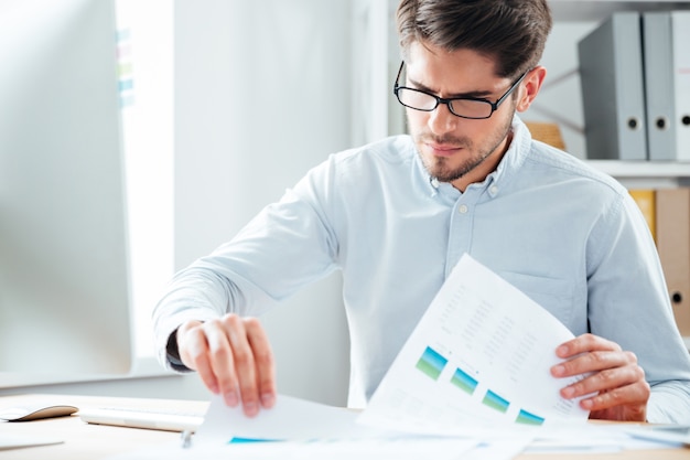 Handsome young businessman working with documents and pc computer in office