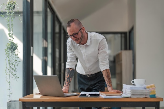 Handsome young businessman working with laptop computer at his desk in office Happy male entrepreneur