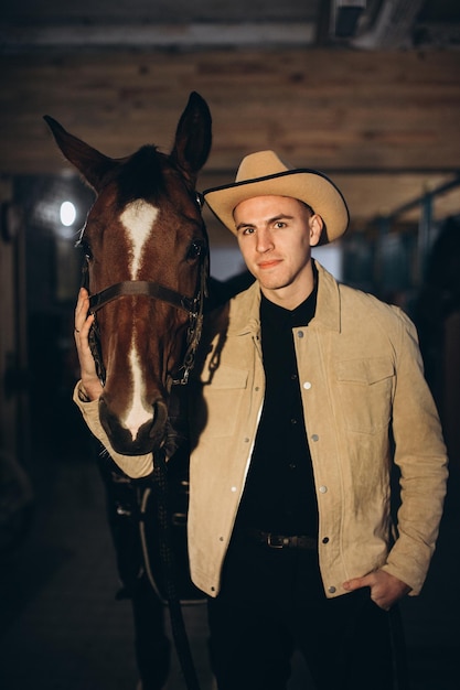 Handsome young cowboy on a ranch with a horse