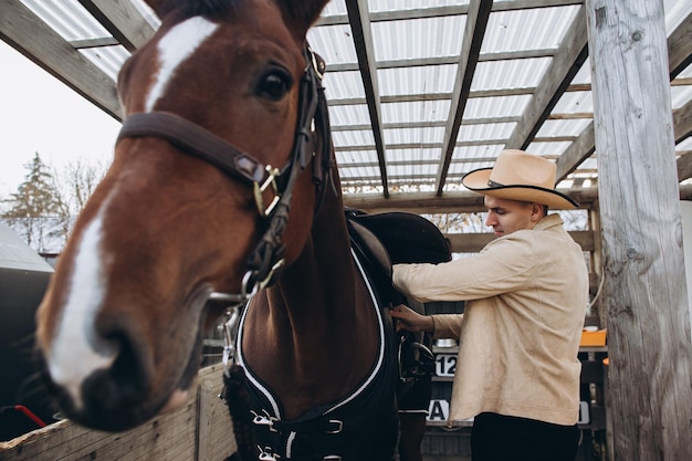 Handsome young cowboy on a ranch with a horse