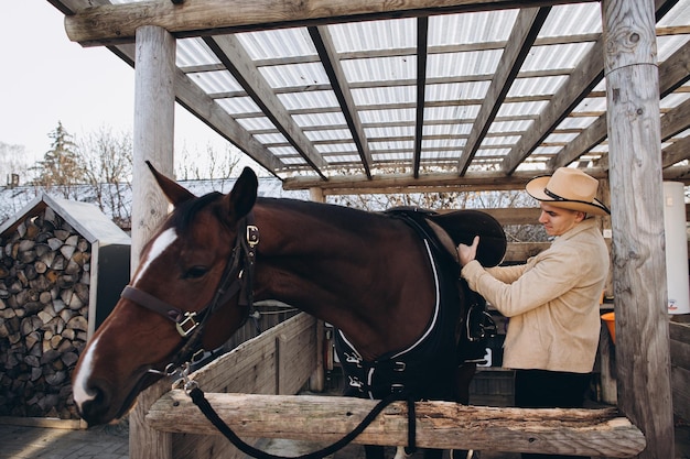 Handsome young cowboy on a ranch with a horse