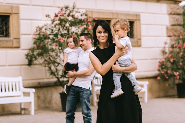 Handsome young father and beautiful mother in sunny summer nature playing with their cute small childrens