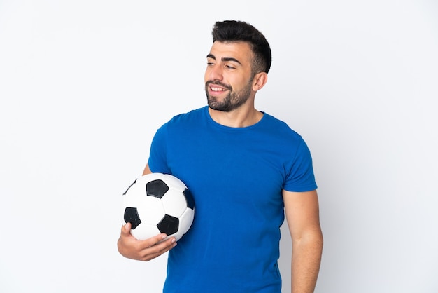 Handsome young football player man over isolated wall looking to the side and smiling