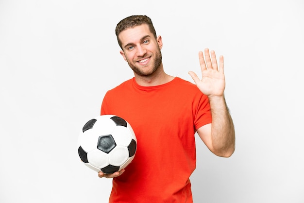 Handsome young football player man over isolated white background saluting with hand with happy expression