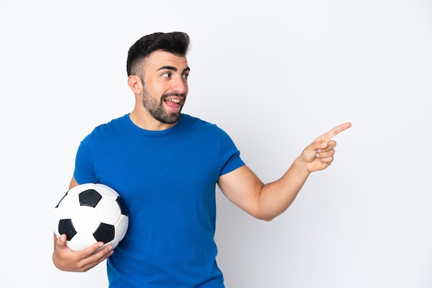 Handsome young football player man over wall pointing finger to the side and presenting a product