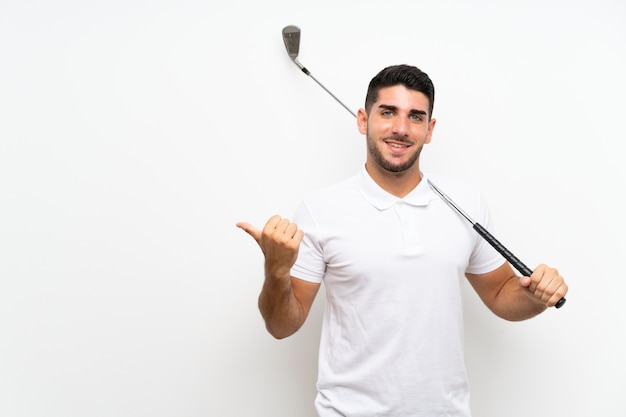 Handsome young golfer player man over isolated white pointing to the side to present a product