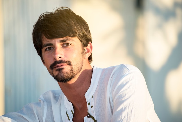 Handsome young guy in holiday sitting outdoors in  summer day looking at camera