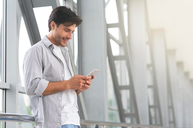 Handsome young guy using smartphone in airport browsing internet