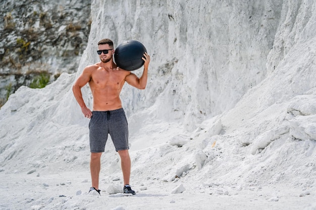 Handsome young macho with naked torso. Strong athletic man working out outdoor.