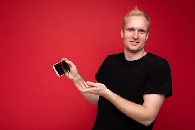 Handsome young male person wearing black tshirt standing isolated on red